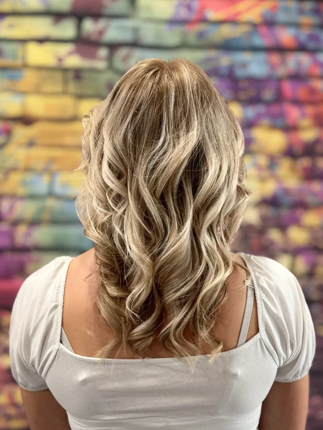 Blond vlny pred farebnou stenou salóna